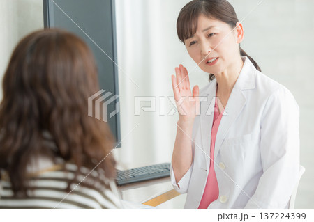 患者に説明する白衣の女性 患者に説明する白衣の女性 137224399
