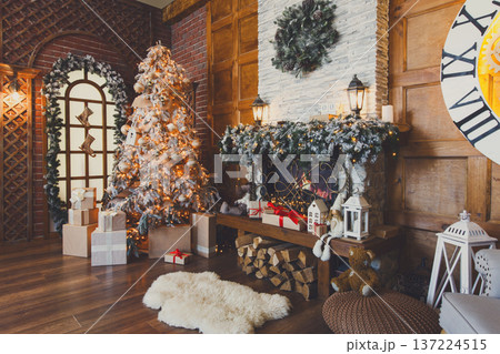 Beautiful christmas interior. Warm room with fireplace, decorated christmas tree, lots of presents and huge clock on wooden wall. Cozy home for winter holidays, copy space Beautiful christmas interior. Warm room with fireplace, decorated christmas tree, lots of presents and huge clock on wooden wall. Cozy home for winter holidays, copy space 137224515