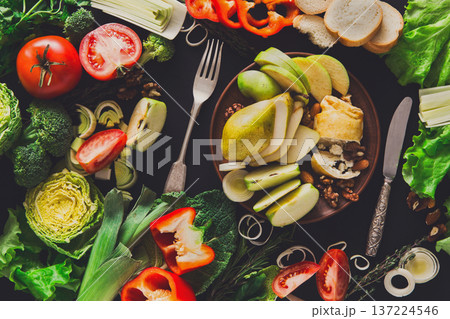 Healthy eating concept. Fresh organic meals and low-fat dessert on brown clay plate at black background. Strudel with cottage-cheese, nuts, apple, pear and vegetables 137224546