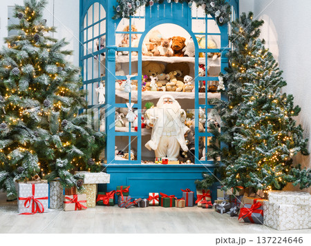 Christmas magical atmosphere background. Modern interior design for winter holidays. Pine trees decorated with shining lights, showcase with toys and present boxes Christmas magical atmosphere background. Modern interior design for winter holidays. Pine trees decorated with shining lights, showcase with toys and present boxes 137224646