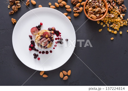 Healthy eating, dieting and detox concept - wholegrain fresh oatmeal porridge on plate with fruits, berries and nuts on dark background. Still life, top view. 137224814