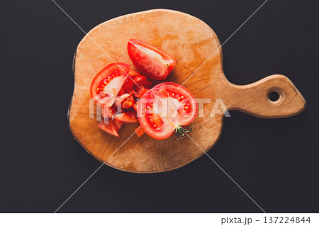 Chopped tomato on wooden board at black background. Cutting fresh vegetable, cooking healthy food Chopped tomato on wooden board at black background. Cutting fresh vegetable, cooking healthy food 137224844
