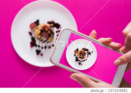 Top view close-up of female hands making flat lay food photo with phone for restaurant menu or social network. Oatmeal porridge on pink background, mockup, template, copy space, shallow depth of field Top view close-up of female hands making flat lay food photo with phone for restaurant menu or social network. Oatmeal porridge on pink background, mockup, template, copy space, shallow depth of field 137224881