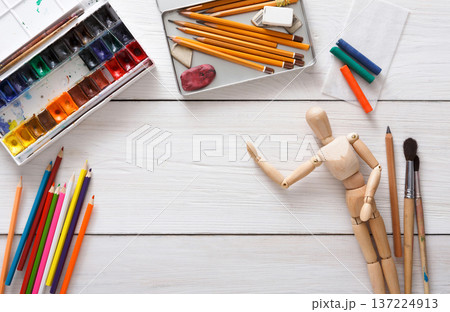 Drawing tools, stationary supplies, workplace of artist. Paints and wooden painter man with brushes on white desk, top view, flat lay, objects 137224913