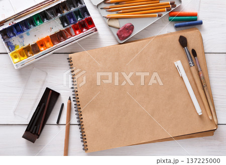 Artist working space background. Watercolor paints and blank craft paper on white wooden desk, top view, flat lay, copy space Artist working space background. Watercolor paints and blank craft paper on white wooden desk, top view, flat lay, copy space 137225000
