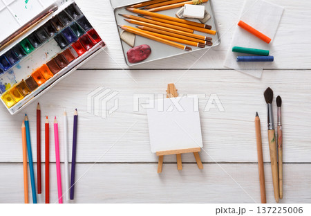 Artist workspace. Drawing tools, stationary supplies, workplace of artist. Watercolor paints and blank paper on white wooden desk, top view, flat lay, copy space 137225006