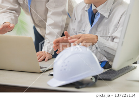 会社で資料を見ながら打ち合わせするエンジニア 137225114