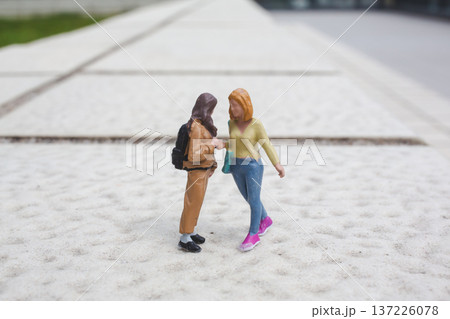 Miniature friends stand talking casually on outdoor concrete walkway Miniature friends stand talking casually on outdoor concrete walkway 137226078