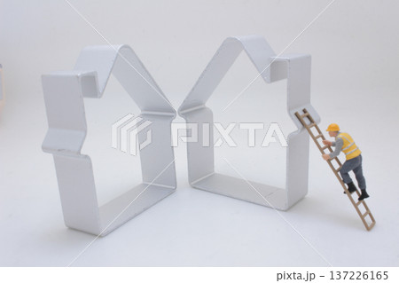 Miniature Worker Climbs Ladder Toward Metal House Frame 137226165
