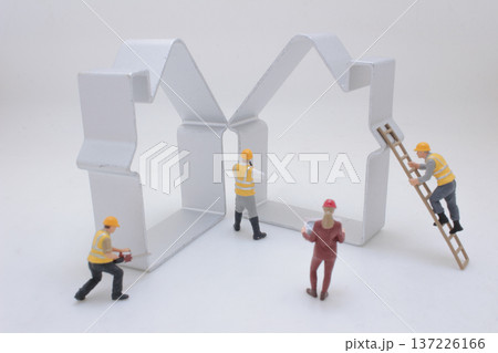 Miniature Construction Crew Works Around Metal House Frames 137226166