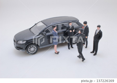 Miniature Figures Stand Together Beside Detailed Black Vehicle 137226169