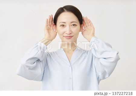耳を澄ます40代の女性 白背景 耳を澄ます40代の女性 白背景 137227218