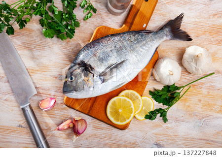 Uncooked dorado fish with lemon, garlic and parsley on wooden table 137227848