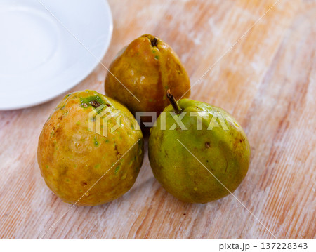 Three fresh ripe unpeeled guavas on wooden background Three fresh ripe unpeeled guavas on wooden background 137228343