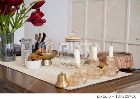 Table setting. Tea ceremony arrangement. Transparent teapot glass with tasty wholegrain snack candles bell for sound therapy flower. 137229410