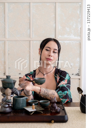 Herbal drink. Chinese tea ceremony. Table with tea-board woman holding water vapor incense ceramics cup figurine. 137229413