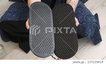 Sadhu board. Yoga tool. Woman sitting in lotus position hand holding sharp nails for practice meditation foot massage spiritual growth. 137229414