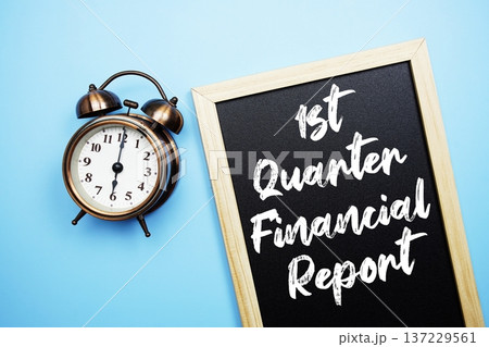 1st Quarter Financial Report text on Blackboard and alarm clock on blue background 137229561