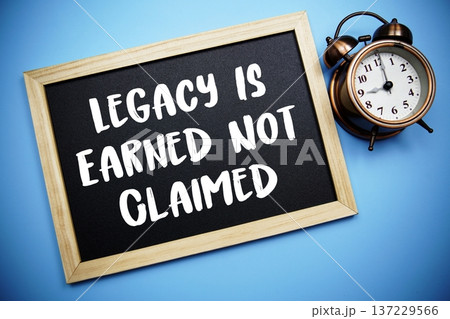 Legacy Is Earned Not Claimed text on Blackboard and alarm clock on blue background 137229566