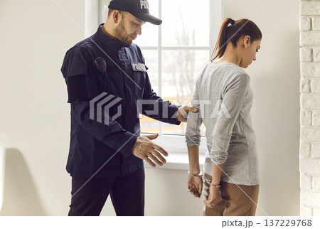 Policeman Arresting Suspect Woman And Placing Handcuffs On Wrists 137229768