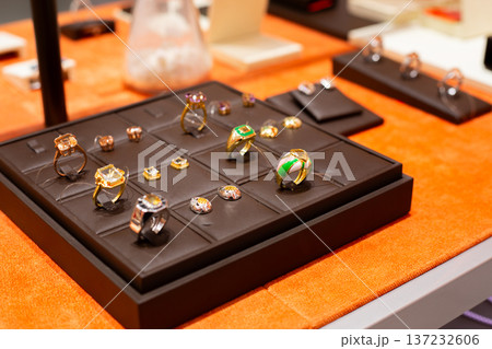 Shelf in jewelry store with set of rings and earrings. Pairs of jewelry in same style. Fine jewelry to highlight unified style. Buying jewelry for elegance and fashion. Jewelry set concept Shelf in jewelry store with set of rings and earrings. Pairs of jewelry in same style. Fine jewelry to highlight unified style. Buying jewelry for elegance and fashion. Jewelry set concept 137232606