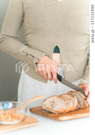 キッチンで朝食にパンをカットする女性の手元 キッチンで朝食にパンをカットする女性の手元 137232898
