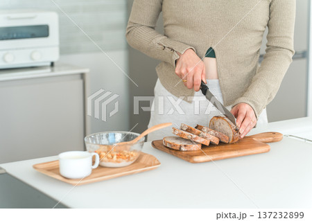 キッチンで朝食にパンをカットする女性の手元 137232899