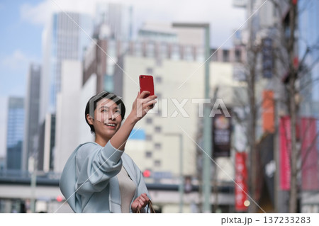 銀座の街をスマートフォンで撮る女性 137233283