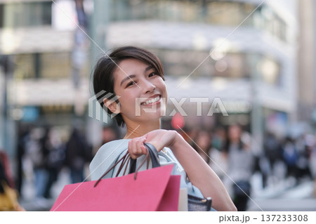 銀座の通りでショッピングバッグを持って微笑む女性 137233308