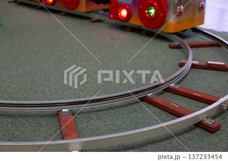 Miniature train set for child to ride in trolley. Scale rails and sleepers on curved track. Train set for children. Developing child future train driver skills Miniature train set for child to ride in trolley. Scale rails and sleepers on curved track. Train set for children. Developing child future train driver skills 137233454