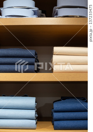 Male perfectionism is expressed in clothes folded on closet shelf. Neatly arranged classic pieces represent man who appreciates order. Folded clothes in wardrobe symbolize desire for perfect clothes Male perfectionism is expressed in clothes folded on closet shelf. Neatly arranged classic pieces represent man who appreciates order. Folded clothes in wardrobe symbolize desire for perfect clothes 137233475