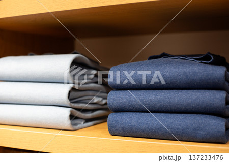 Folded and ironed items on man wardrobe shelf. Predictable clothes in businessman closet with casual look. Identical clothes in man wardrobe. Classic style in wealthy man wardrobe Folded and ironed items on man wardrobe shelf. Predictable clothes in businessman closet with casual look. Identical clothes in man wardrobe. Classic style in wealthy man wardrobe 137233476