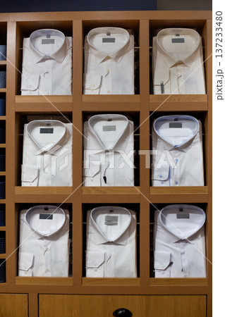 Closet full of classic shirts on display at store features white collared shirts in various shades of white. Cloud Dancer white and other modern white shades. Choose your white color for clothing 137233480