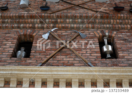 Medieval workshop with crossed axes at entrance to building. Weapon making in ancient times. Military development of state through personal weapons. Axe as weapon of war. Exterior of military barrack 137233489