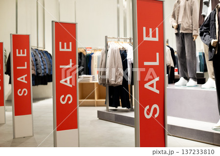 Red anti theft security gates at store entrance dressed in sale covers. Retail shop doorway advertising seasonal discounts. Concept of sale, special offers, and loss prevention integration 137233810