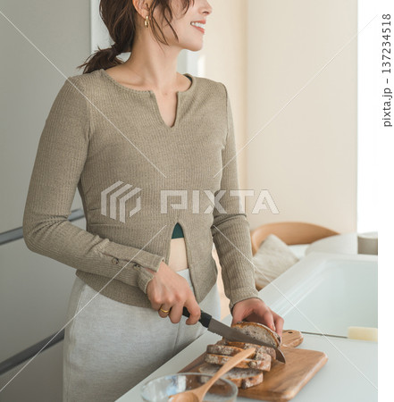 キッチンで朝食にパンをカットする女性 キッチンで朝食にパンをカットする女性 137234518