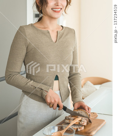 キッチンで朝食にパンをカットする女性 137234519