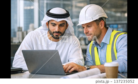 Onsite Consultation With Engineer And Client Discusses Designs, Engineer And Arab Client Analyze Construction Blueprints Together On Location With International Team 137235052