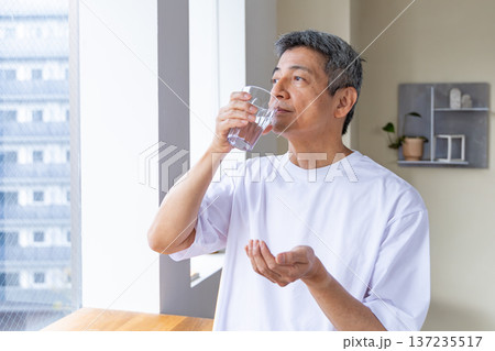 窓辺で薬を飲むシニア男性 137235517