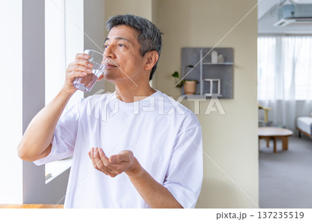 窓辺で薬を飲むシニア男性 窓辺で薬を飲むシニア男性 137235519