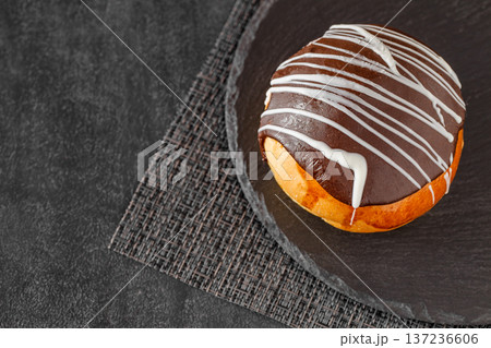Chocolate icing cake on slate stone plate round, dark background, selective focus Chocolate icing cake on slate stone plate round, dark background, selective focus 137236606