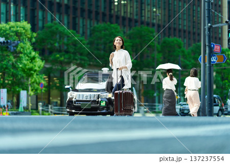 スーツケースを持って街を歩く女性 137237554