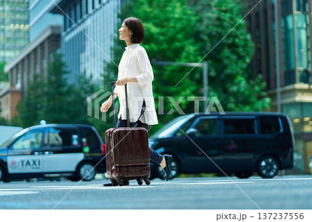 スーツケースを持って街を歩く女性 137237556