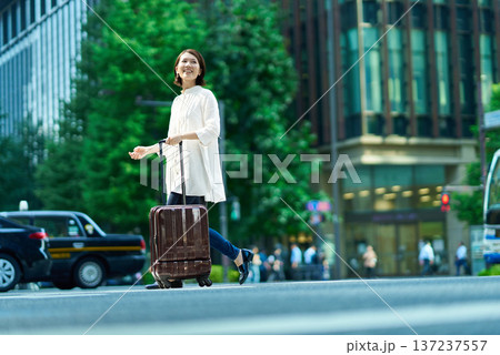スーツケースを持って街を歩く女性 137237557