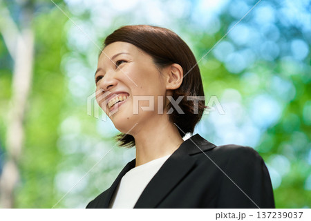 屋外で笑顔を見せるビジネスウーマン 137239037