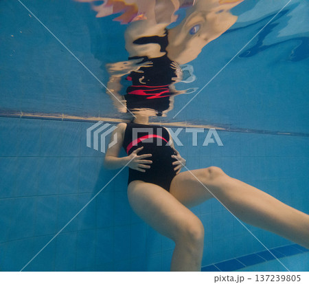 Pregnant woman floating underwater in swimming pool Pregnant woman floating underwater in swimming pool 137239805