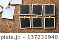 set of four blank photo frames, each with a white background and black border, is neatly displayed in the top left corner of an old-fashioned brown wooden corkboard covered in other white sticky notes 137239940