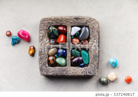 Colorful Tumbled Gemstones in Rustic Stone Tray on Light Surface 137240617