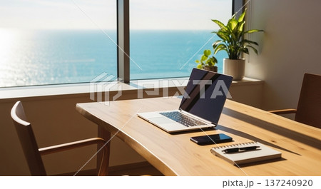 木製デスク上の携帯型計算機と業務資料表示画面の室内風景 137240920
