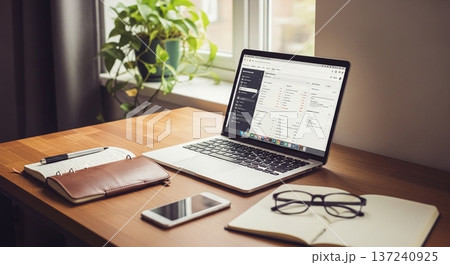 木製デスク上の携帯型計算機と業務資料表示画面の室内風景 137240925